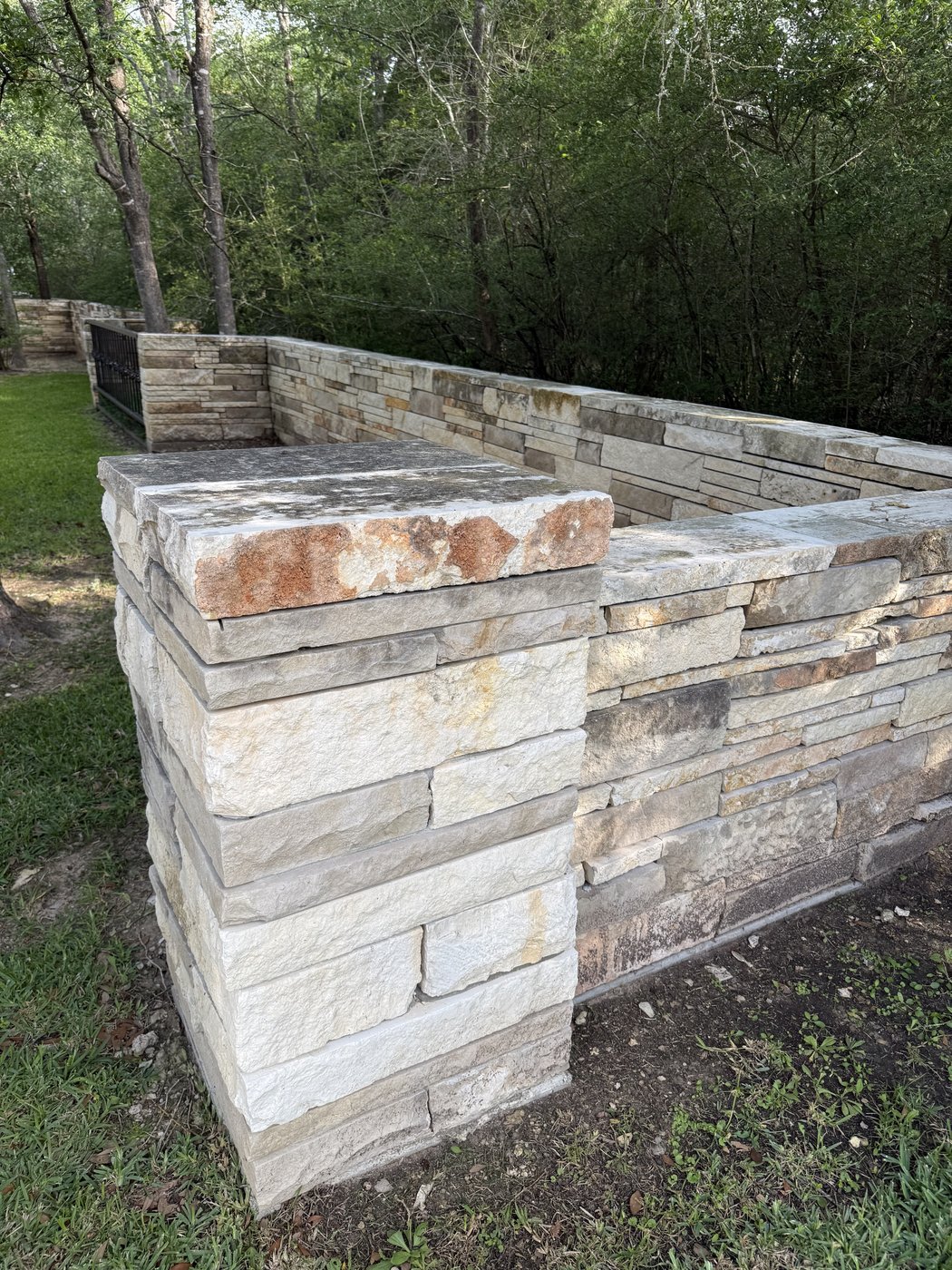 Rusted Earth mixed with Castle Grey in a 2-4-6 pattern — column with a flat cap anchoring stacked planter walls in a tree-shaded garden