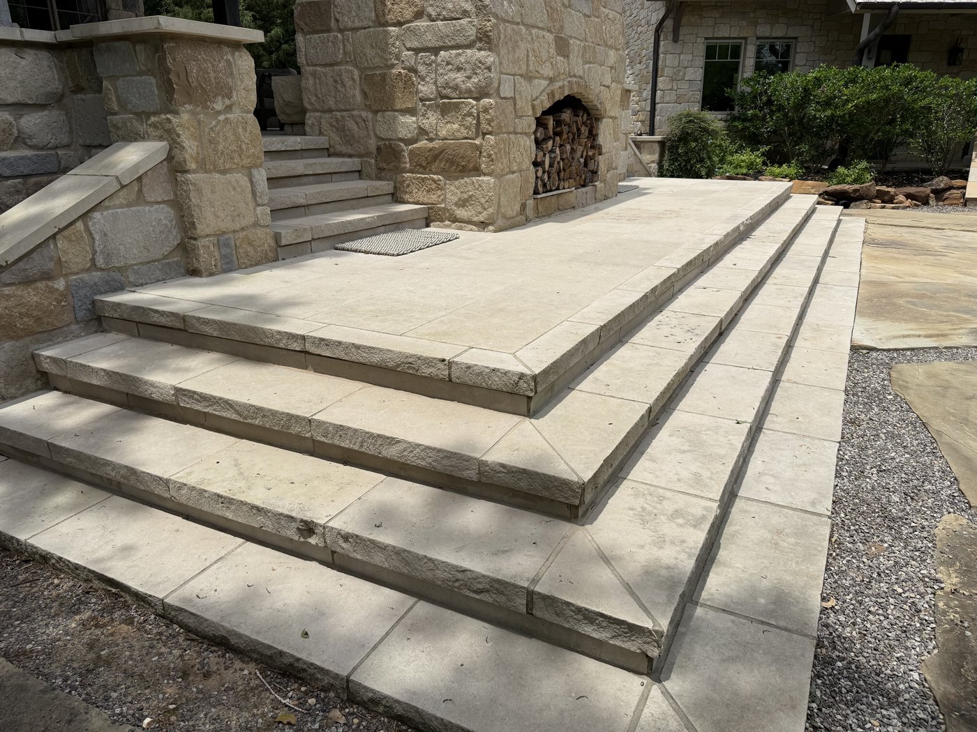 Granada Grey steps and patio leading to an outdoor stone fireplace and chiseled column entry