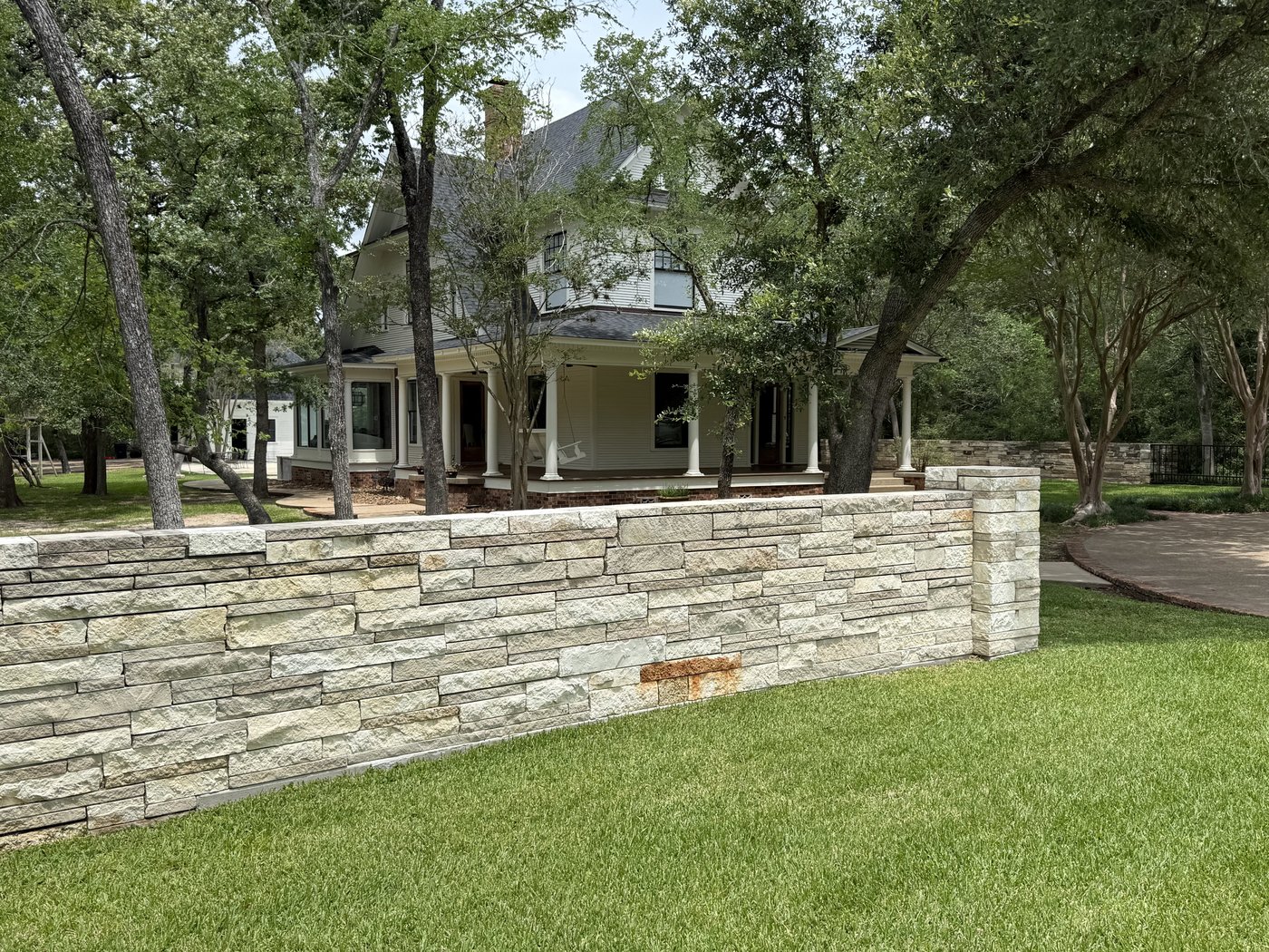 Cream and Castle Grey 2-4-6 garden wall with a flat cream cap framing the lawn in front of a center-entry residence
