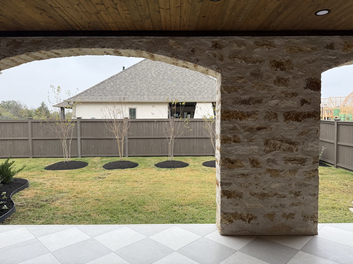 Italian villa side porch — Cavestone arched columns framing the backyard with Granada Grey patio tiles