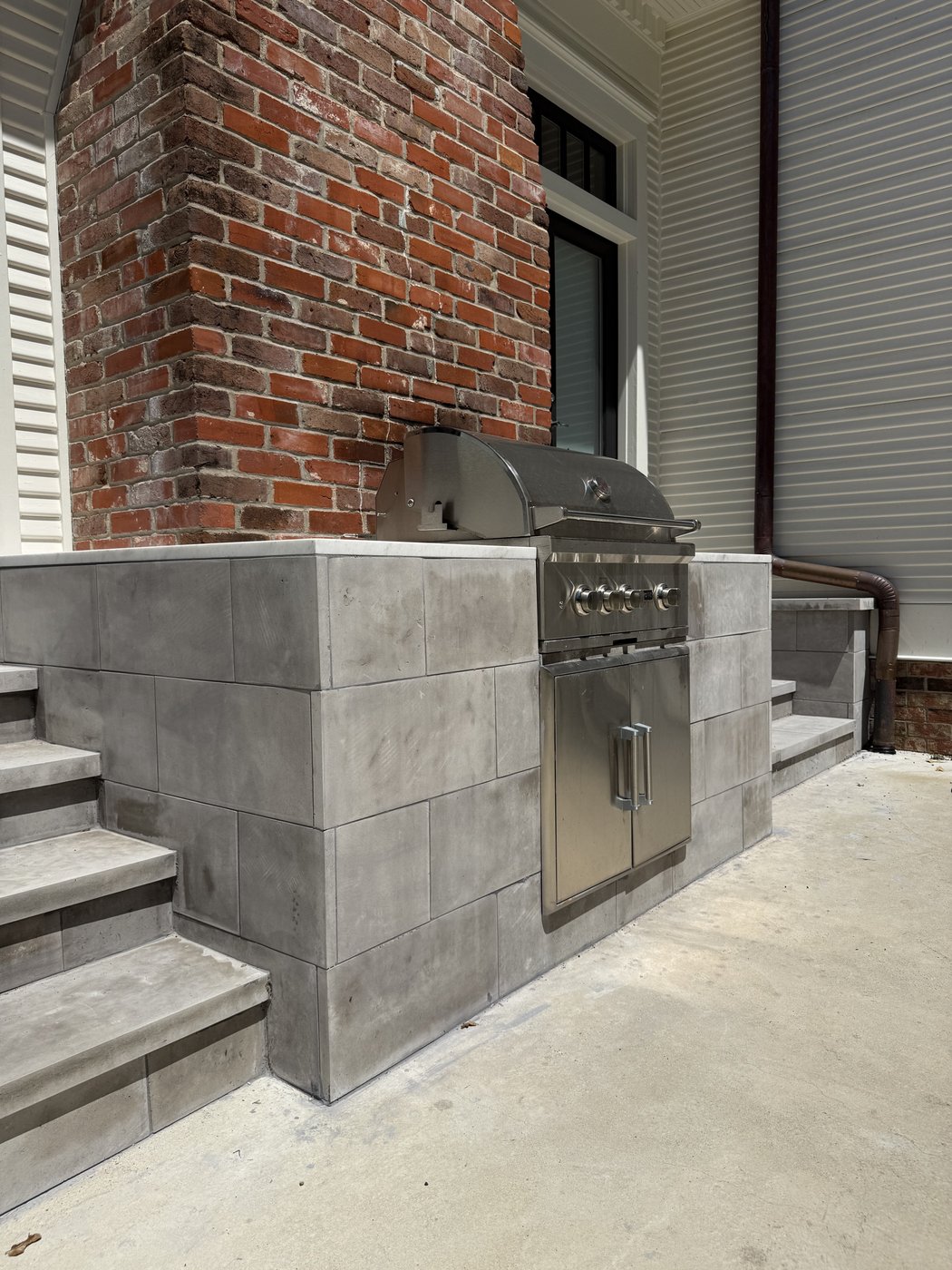 Outdoor kitchen surround in honed charcoal 1 inch tile with 2 inch treads on the side stairs, against a brick column