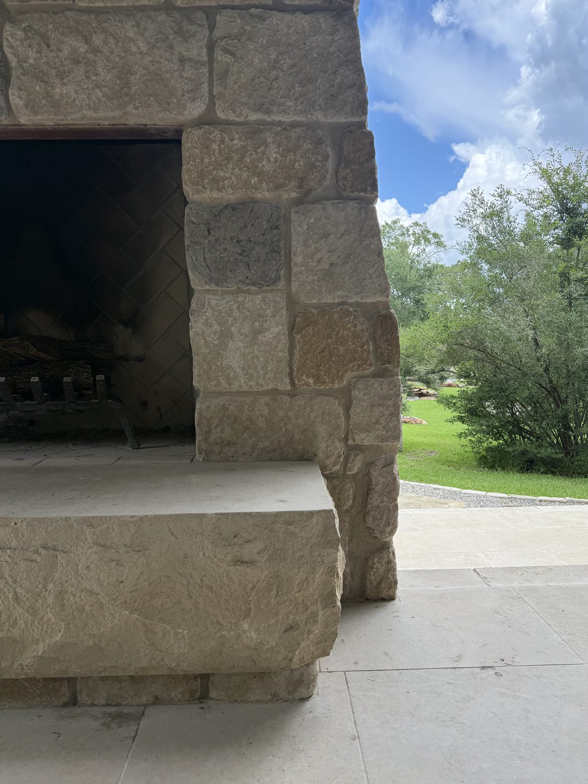 Outdoor fireplace — close-up of the hand-chiseled rusticated stones around the firebox opening with herringbone firebrick floor visible inside