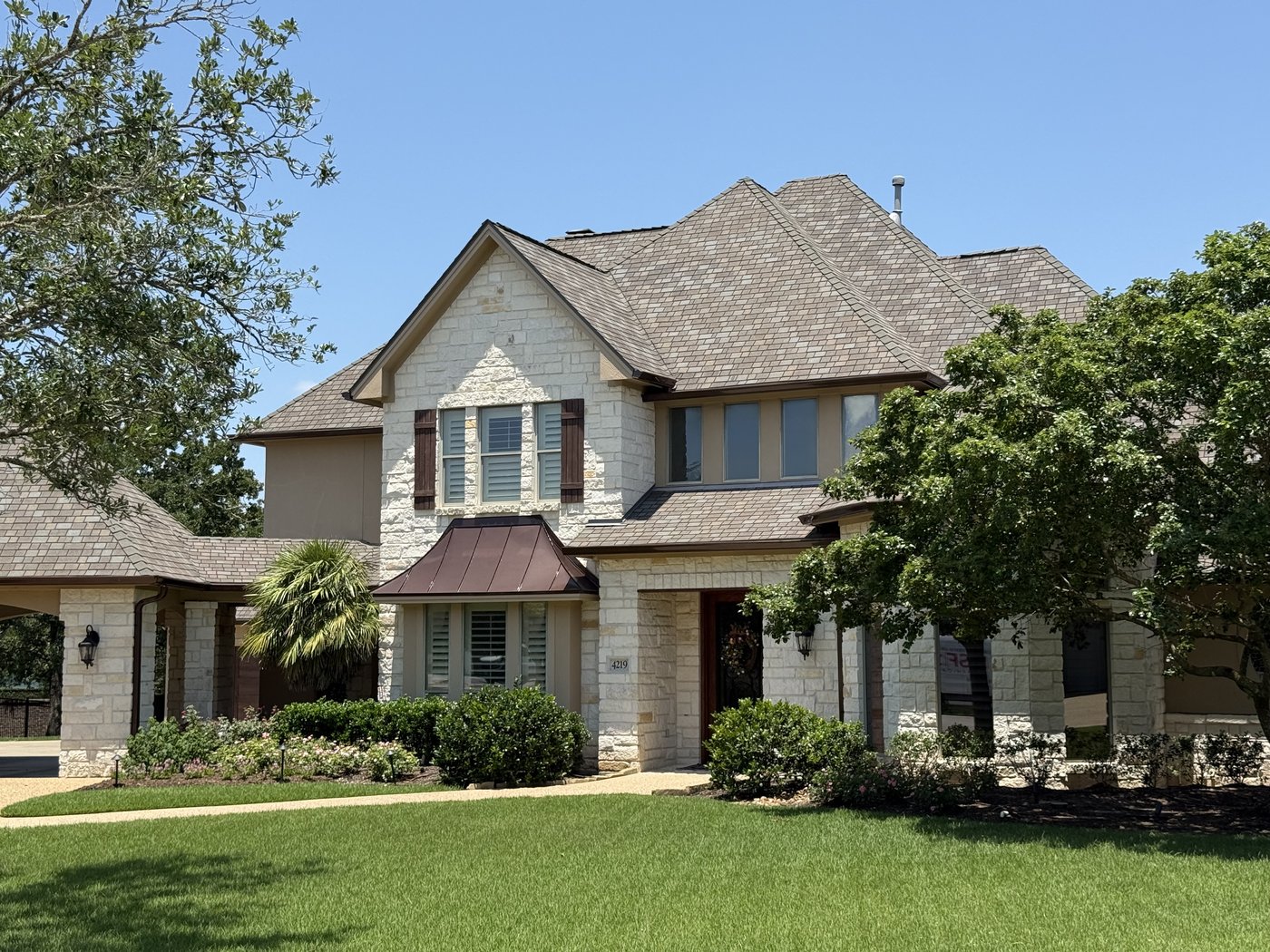 Two-story Hill Country residence — cream 4-6-8 dimensional ashlar with copper bay window and dormers