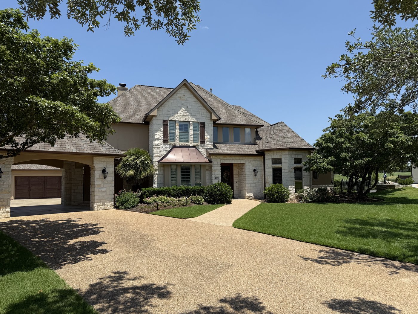 Two-story Hill Country residence — cream 4-6-8 dimensional ashlar, wide view with driveway approach