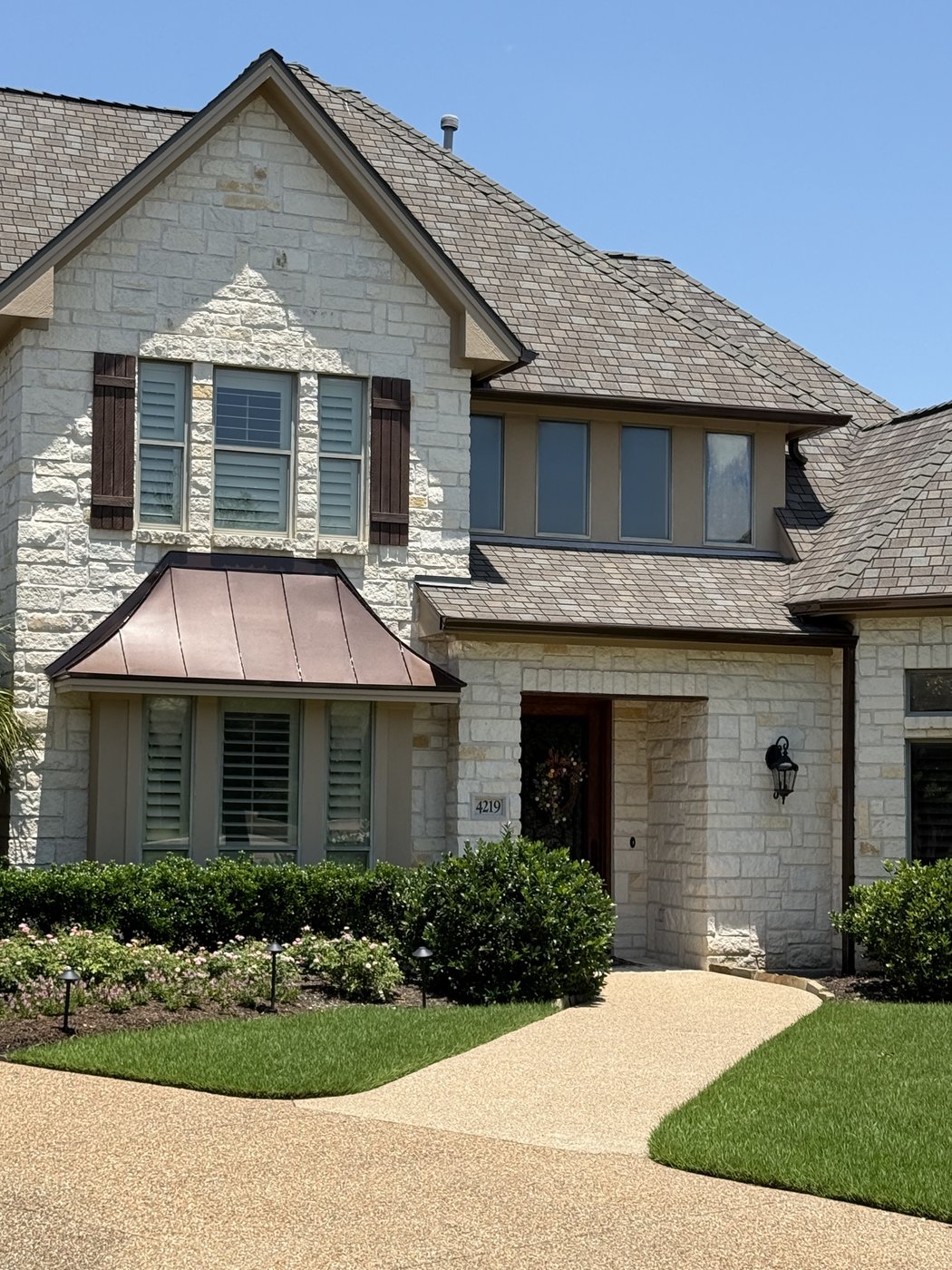 Two-story Hill Country residence — copper bay window and cream 4-6-8 ashlar dormer detail