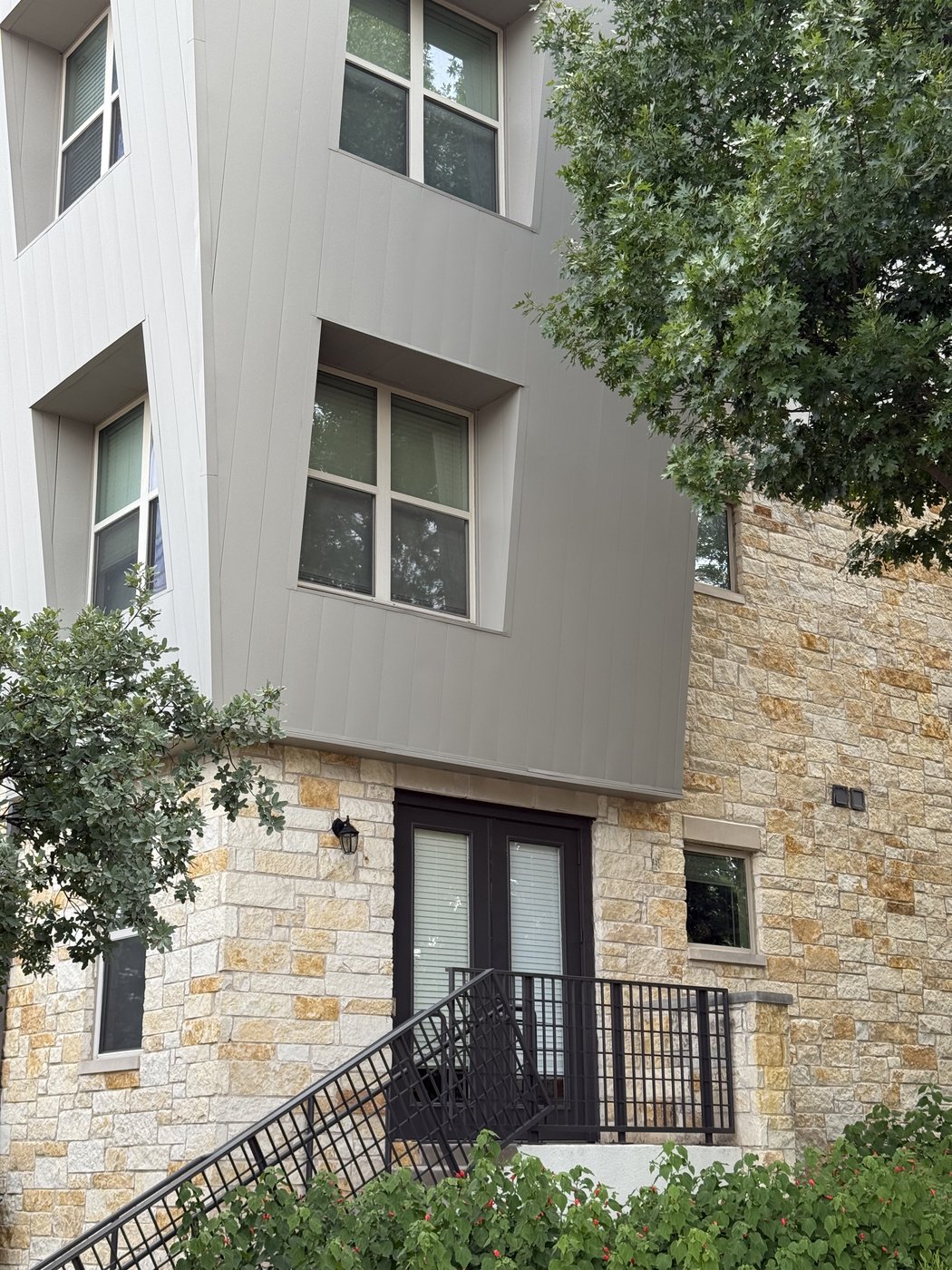 Apartment complex — Goldstone facade with metal stair, dark-trim windows, and stucco above