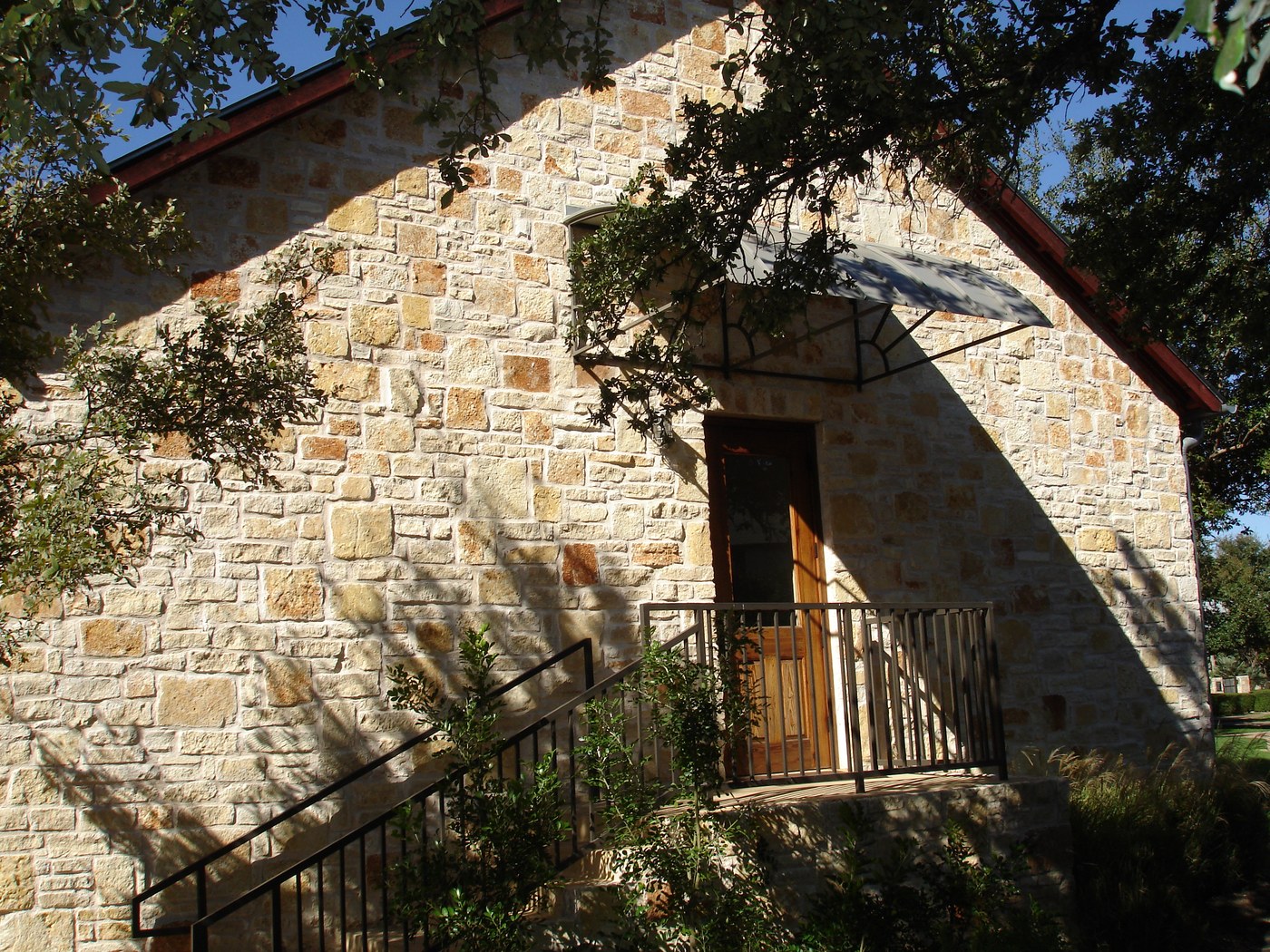 Hill Country residence — Rattlesnake Chop random ashlar gable end with side door and oak canopy