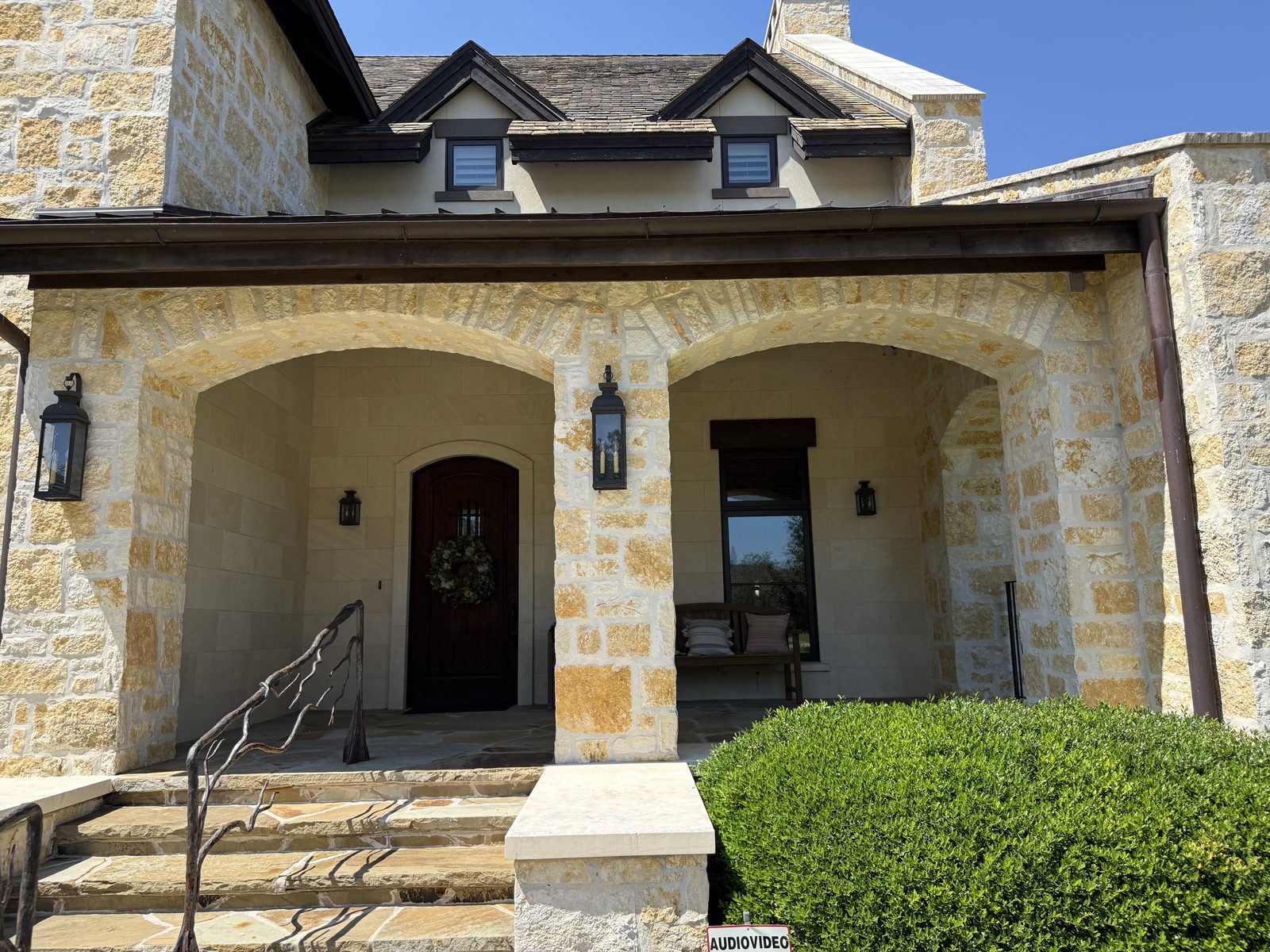 Hill Country residence — Rattlesnake Chop random ashlar with oversize feature pieces, covered front porch with three arched openings and twin dormers
