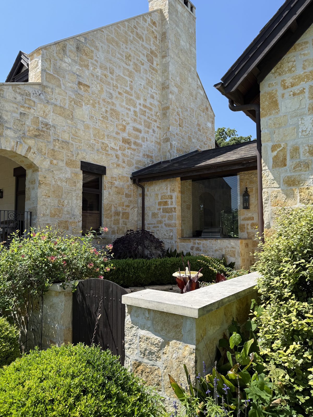 Hill Country residence — Rattlesnake Chop random ashlar side elevation with picture window and low stone planter wall