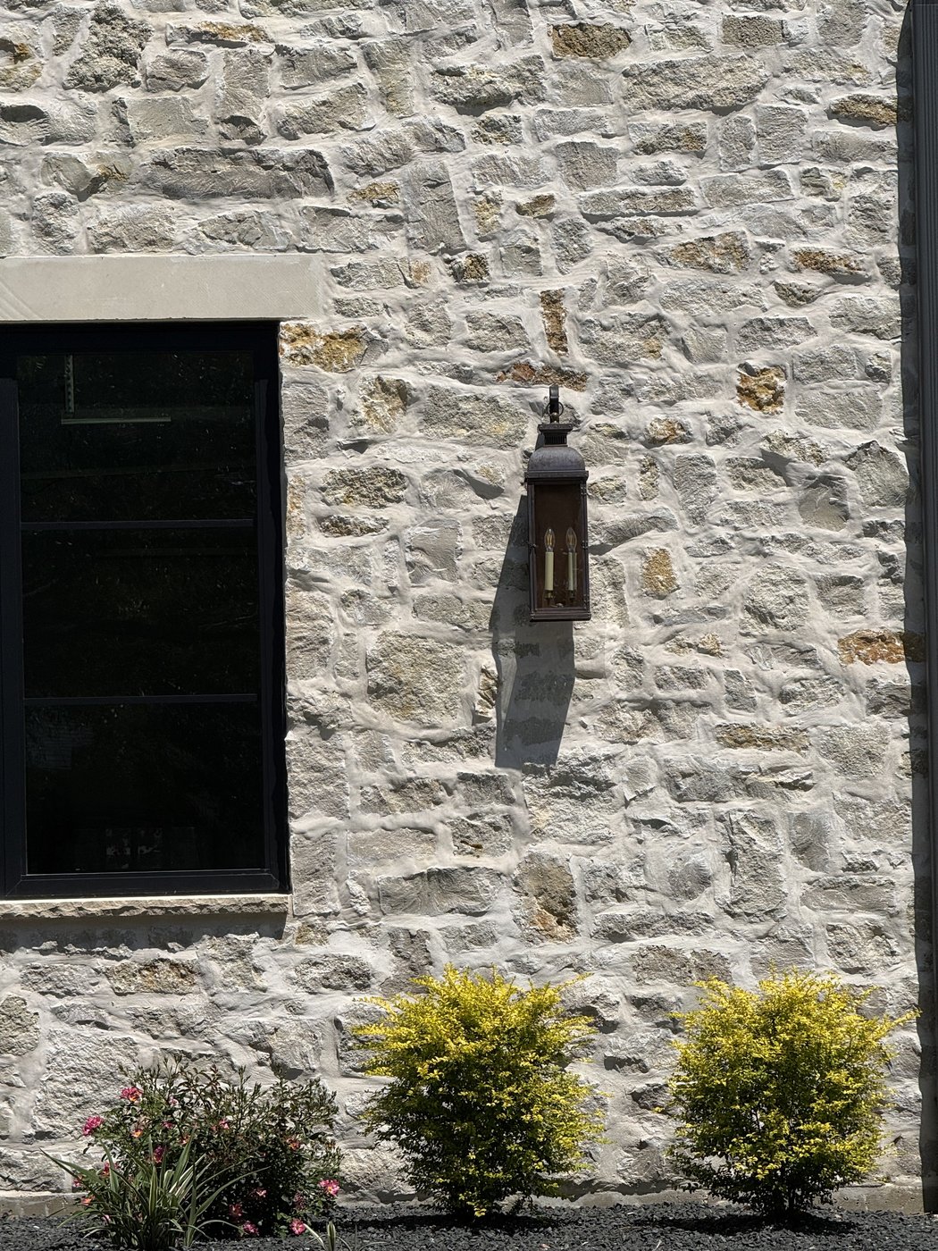 Rubble Rock random ashlar texture close-up with a wall-mounted lantern and yellow lantana blooms
