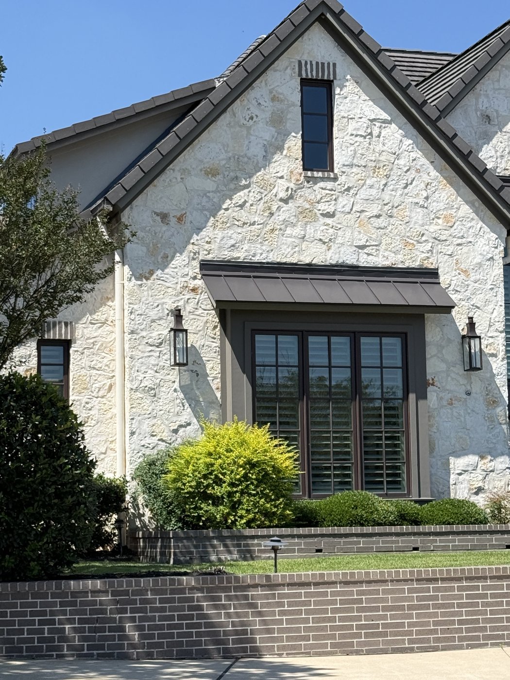 Steep-gable residence — Shell flagstone gable detail with multi-pane sash window and lanterns