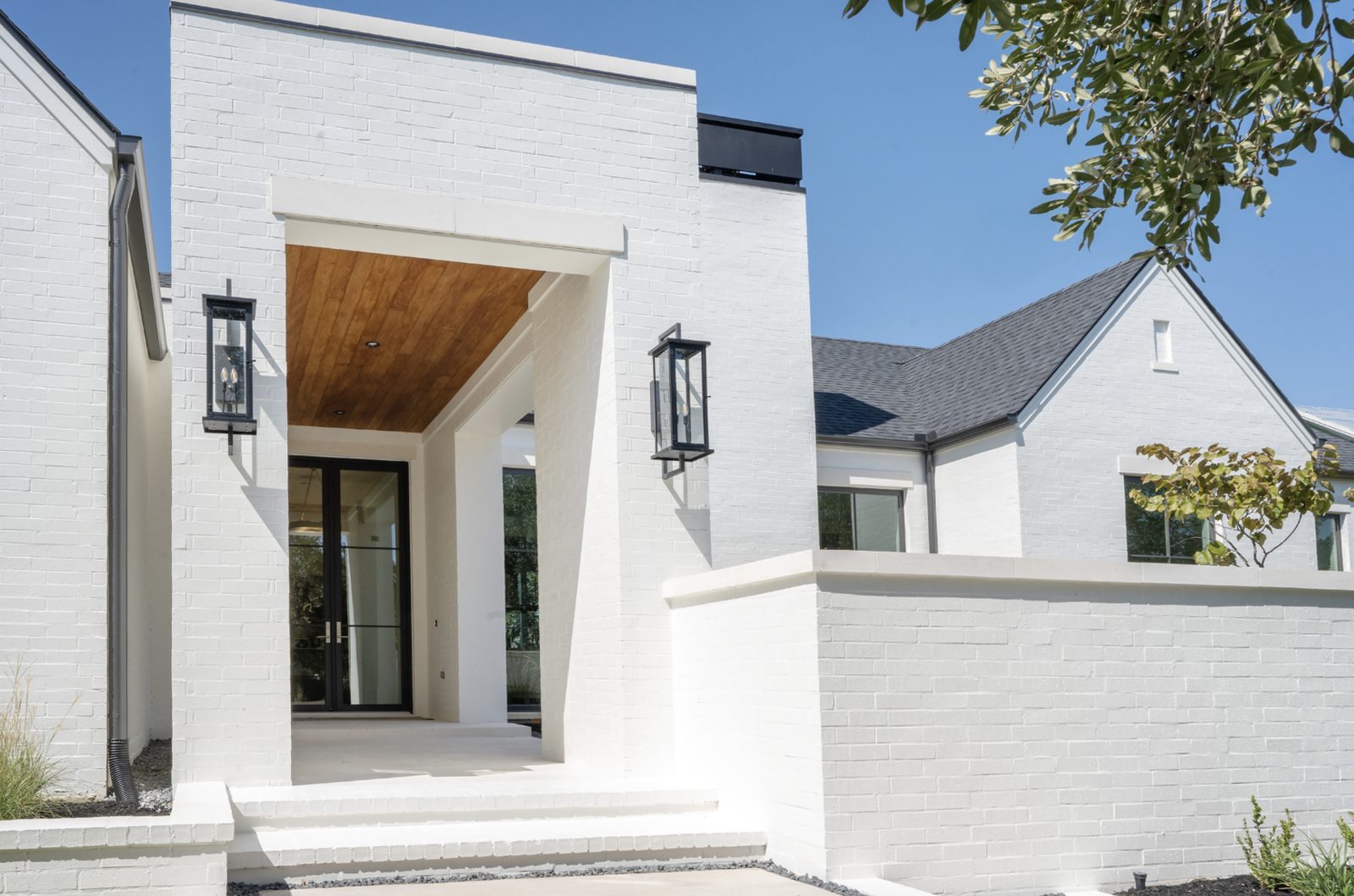 Modern white-brick entry with white limestone wall caps on the low kneewall in the foreground and a white limestone header above the door
