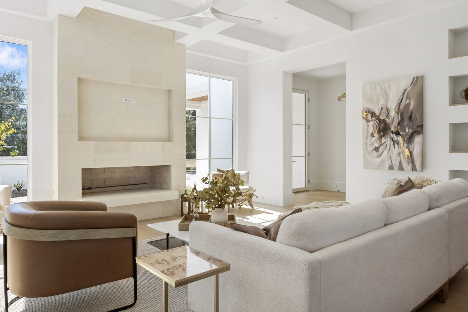Whitewing limestone fireplace at left of frame with raised firebox and recessed niche above, leather chair and sofa in foreground