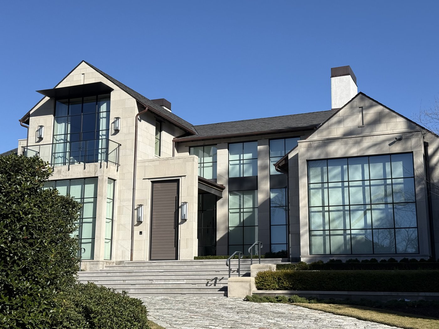 Modern contemporary residence — Whitewing architectural cut stone facade with floor-to-ceiling glass and gabled roof