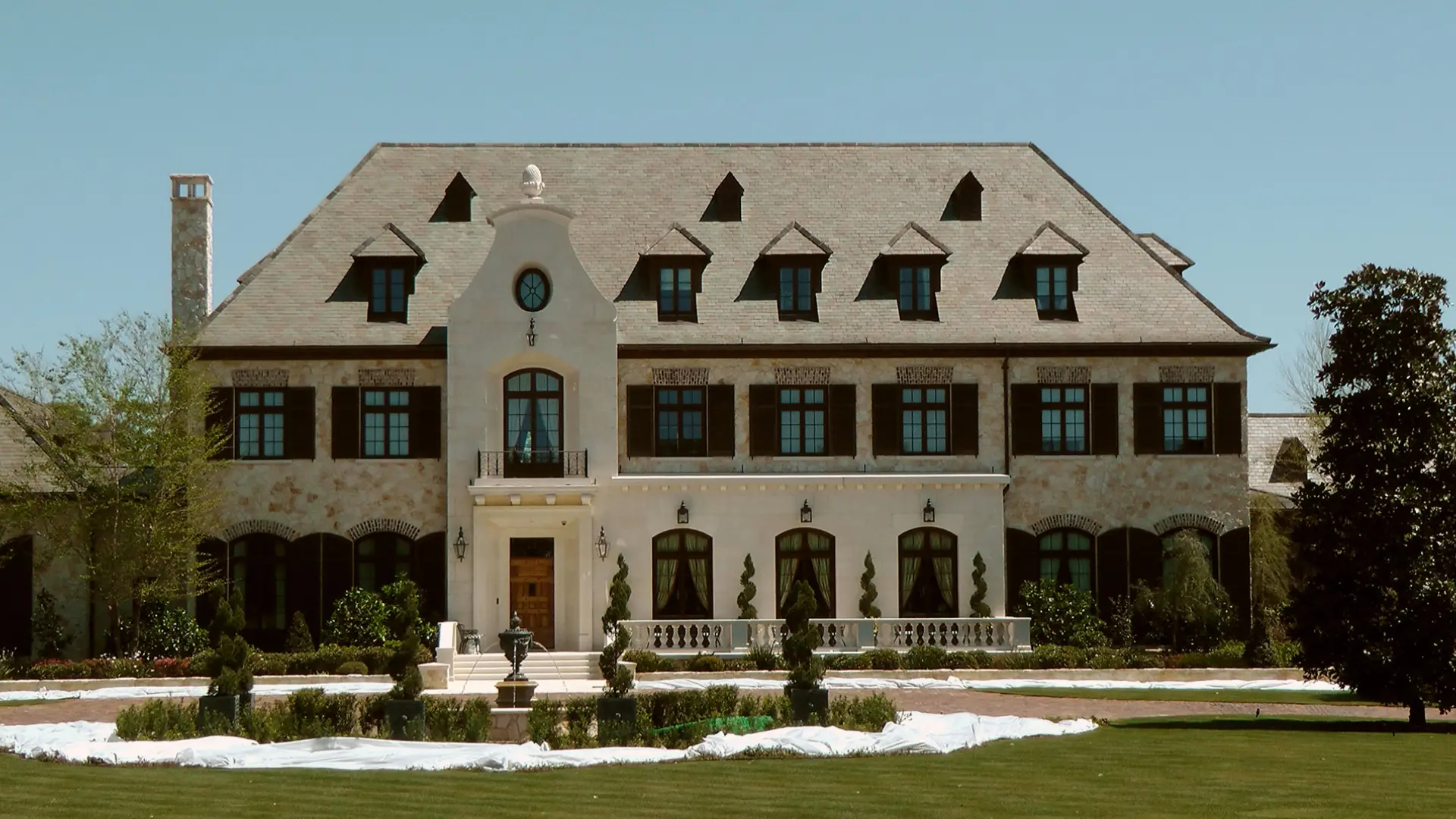 A large white house with a clock on the front of it.