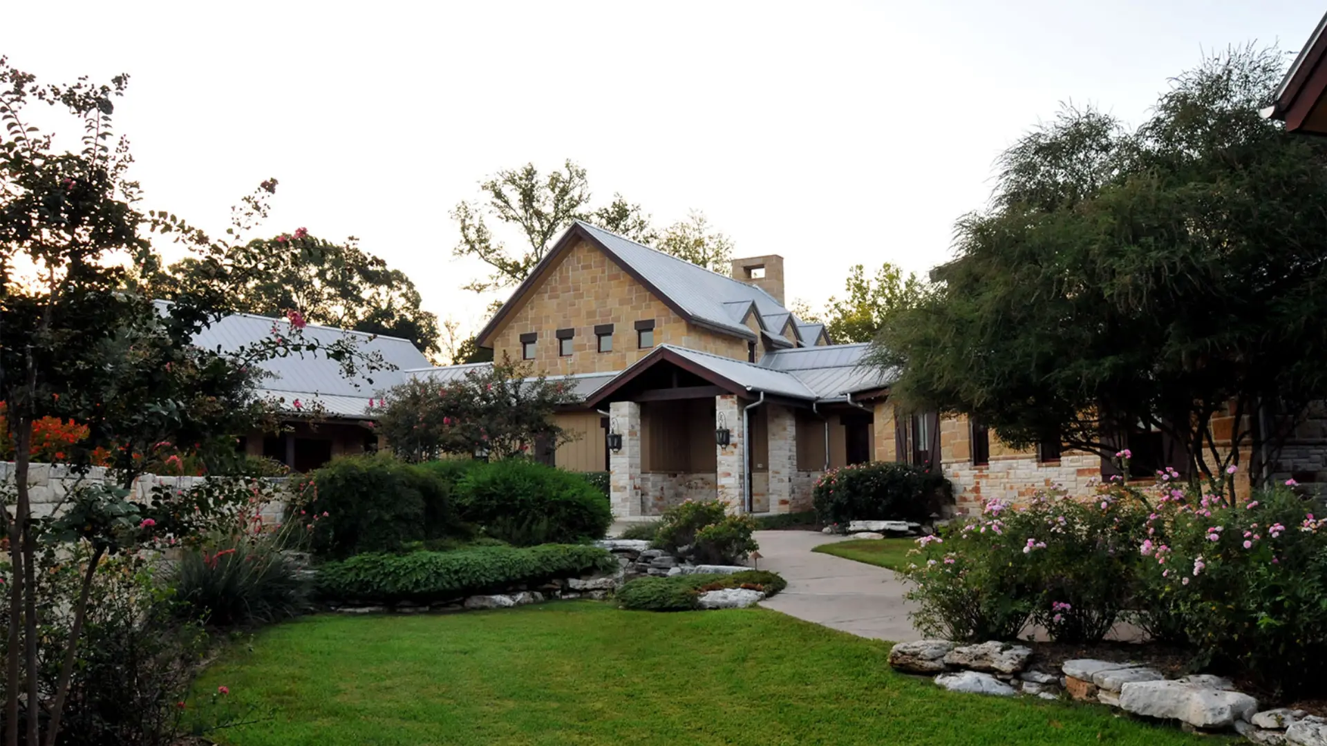 A large stone house with a garden in the front yard.