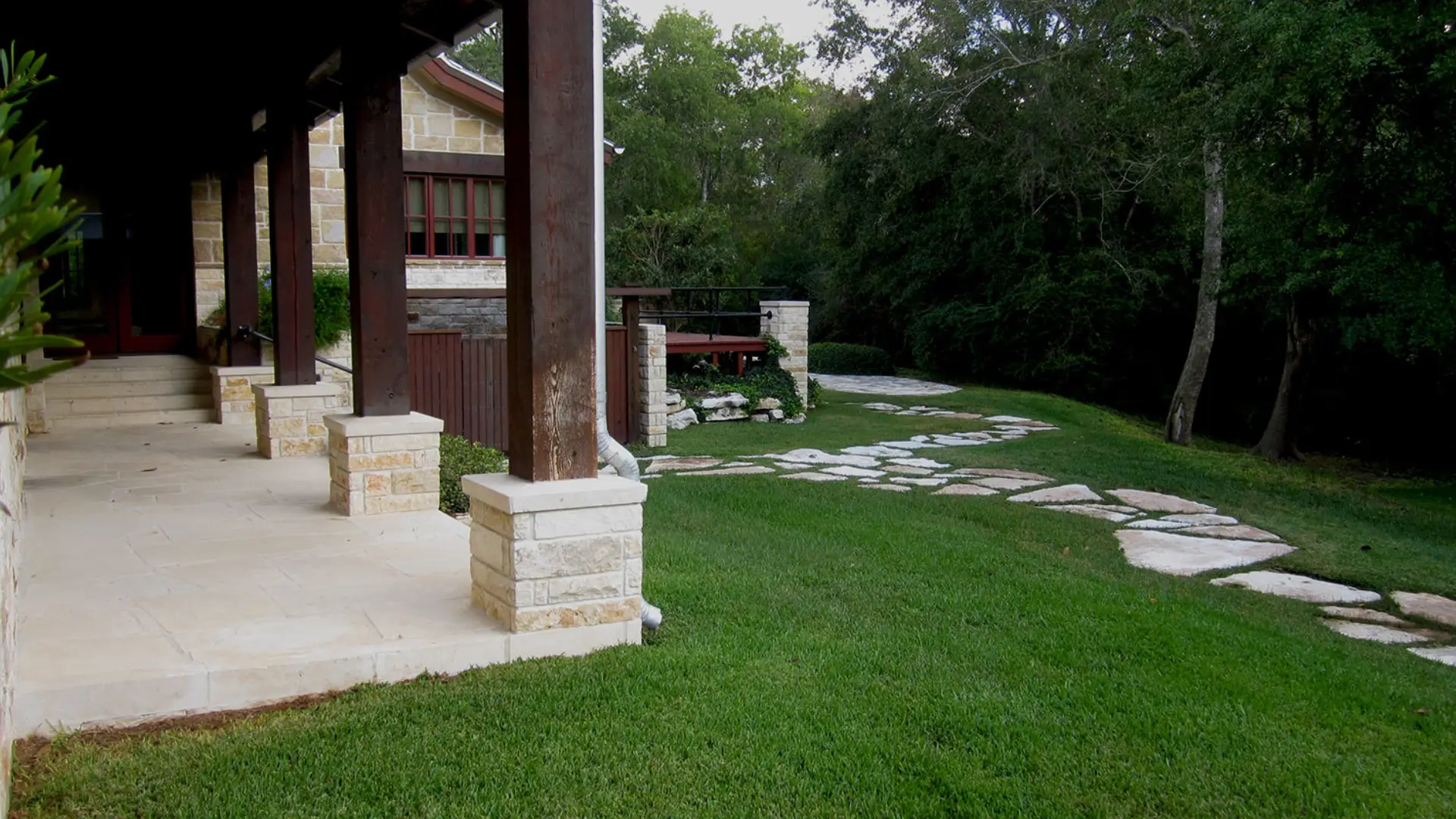 A patio with grass and benches in the background.