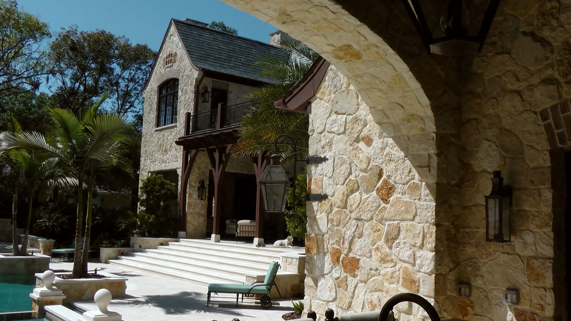 A stone house with a patio and steps leading to the front door.