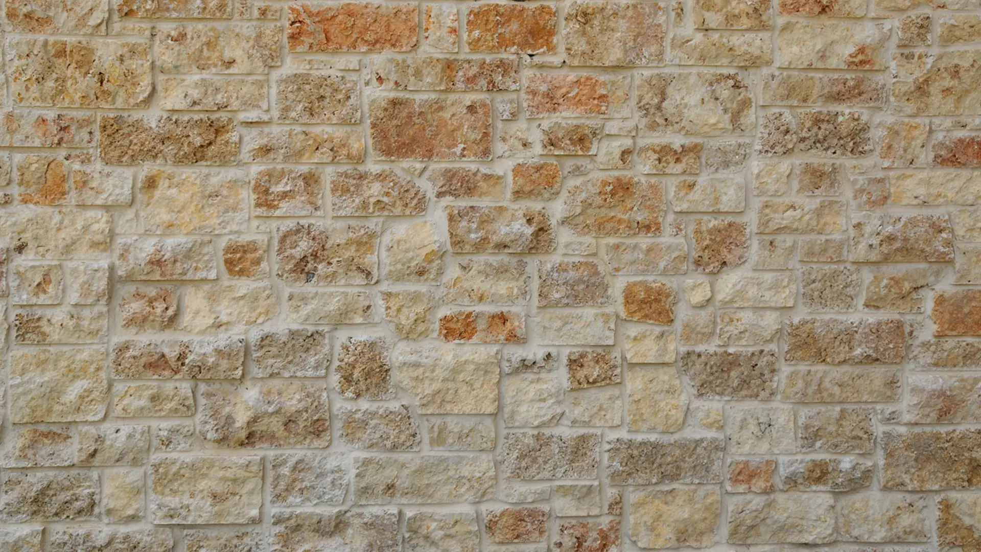 A brick wall with many different colors of stone.