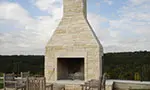 A stone fireplace with chairs around it